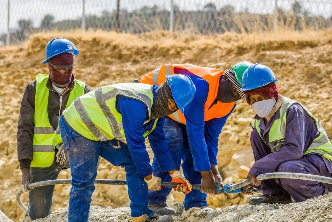 African workers in safety gear working together on site